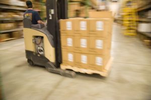 man on forklift moving a stcak of boxes